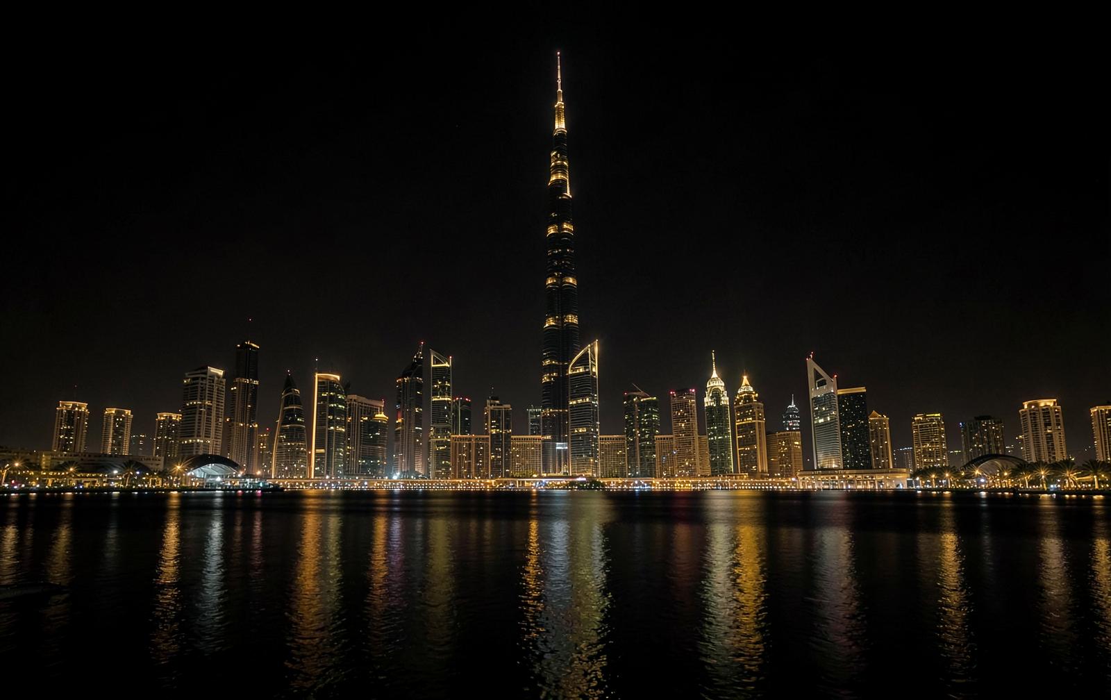 Cinematic night view of the Dubai skyline in dark charcoal and brass tones representing REZALTZ Dubai tax-free structuring